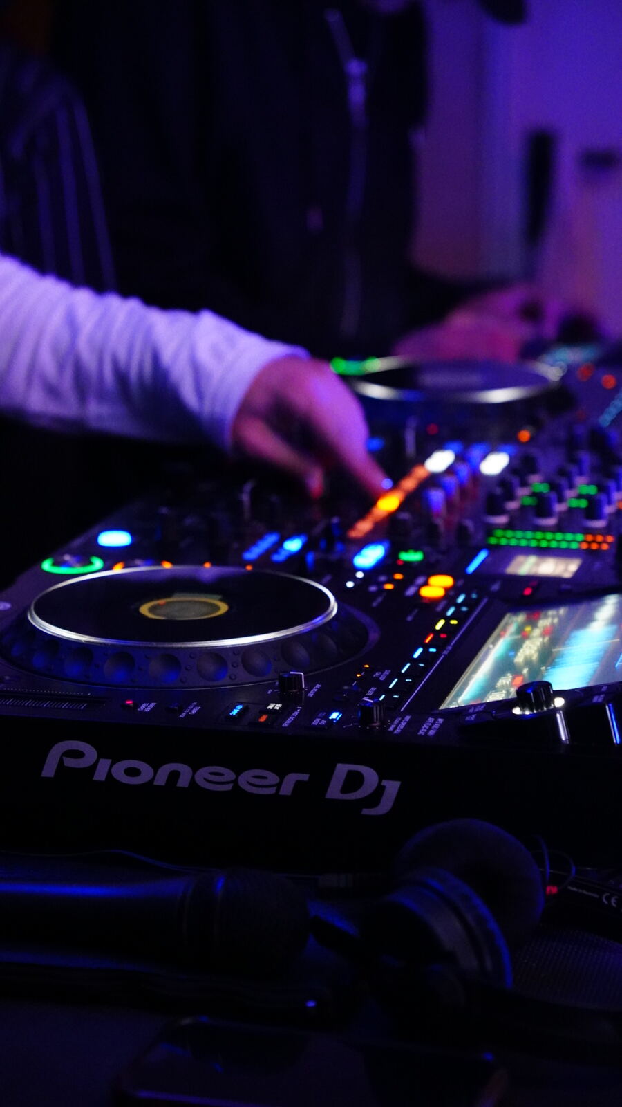 DJ am Mischpult im violetten Partylicht