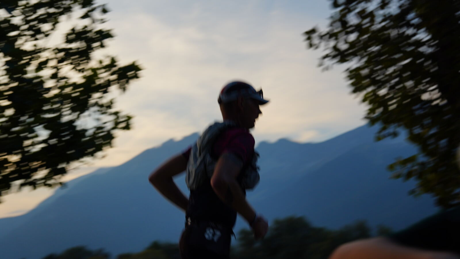 Trailläufer in der Abenddämmerung vor den Bergen